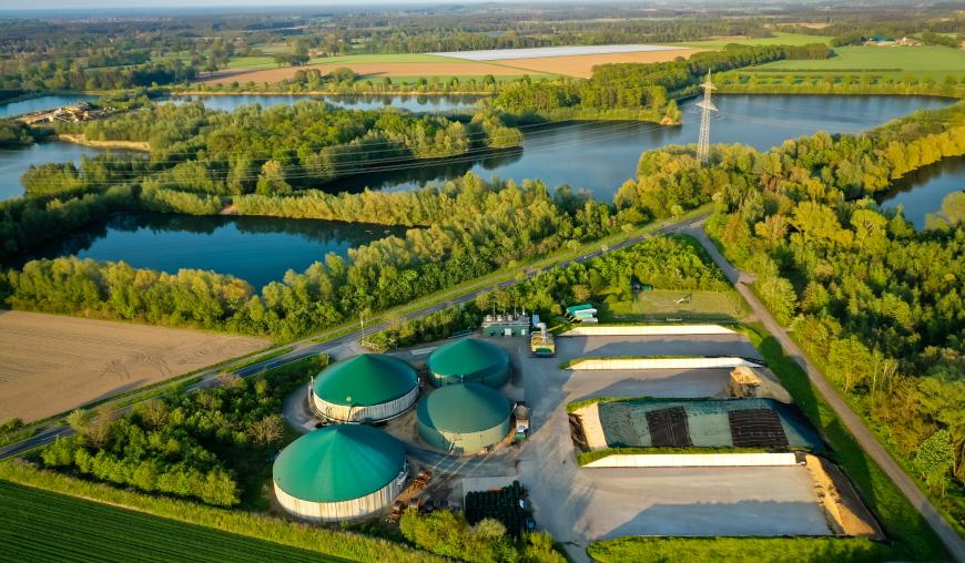 Ansicht einer Biogasanlage von oben, umgeben von Waldflächen und Gewässern